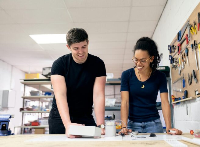 Two engineers collaborate in a workshop, engaging in hands-on prototyping and design.